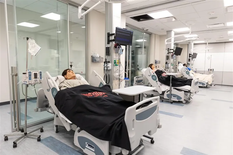 Image of patient care simulation lab with nursing mannequins in hospital beds.