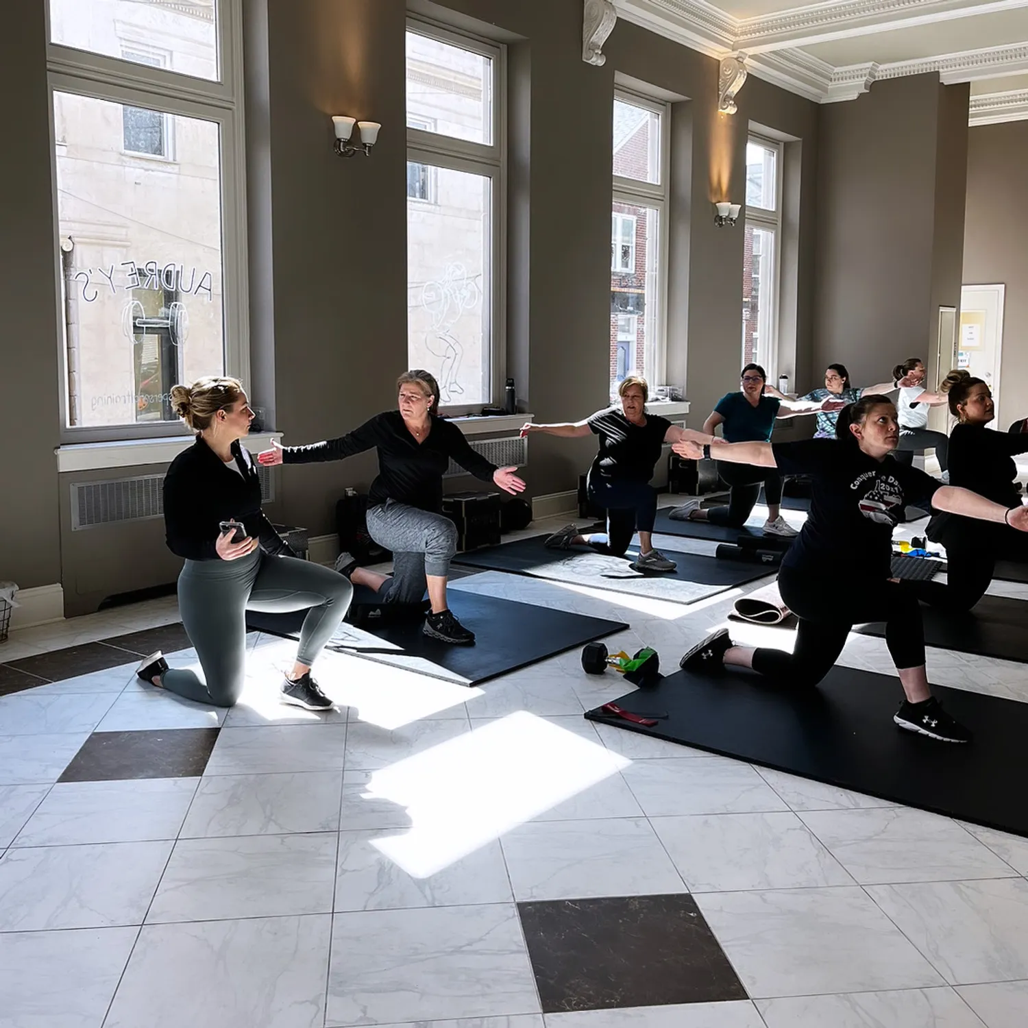 Image of people taking a fitness class inside an old bank building with marble floors.