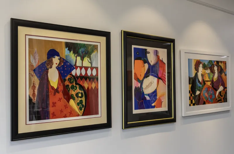Three brightly-colored paintings hang on a white gallery wall.