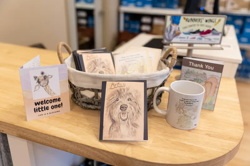 Art work, cards, and mugs on display at Runners' Wings shop.