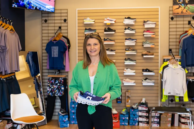 Owner of Runners' Wings in Frostburg, Maryland stands in her shop holding a shoe.