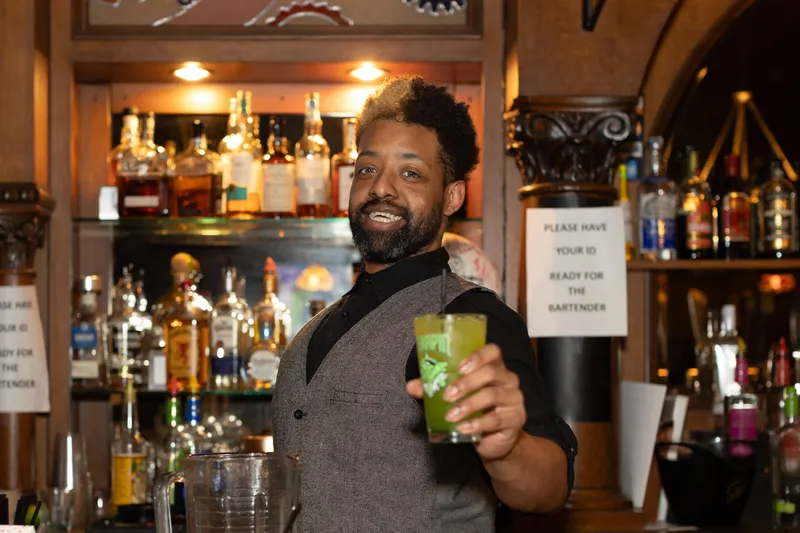 Bartender holds out a drink behind the bar of MEZZOS restaurant in downtown Cumberland.