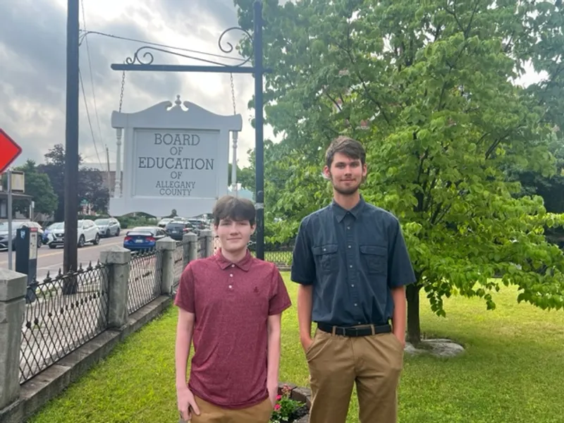 Two P-Tech interns stand in front of the Allegany Board of Education Sign