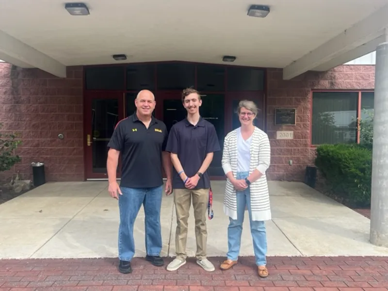 Two supervisors and one intern stand outside of a brick building