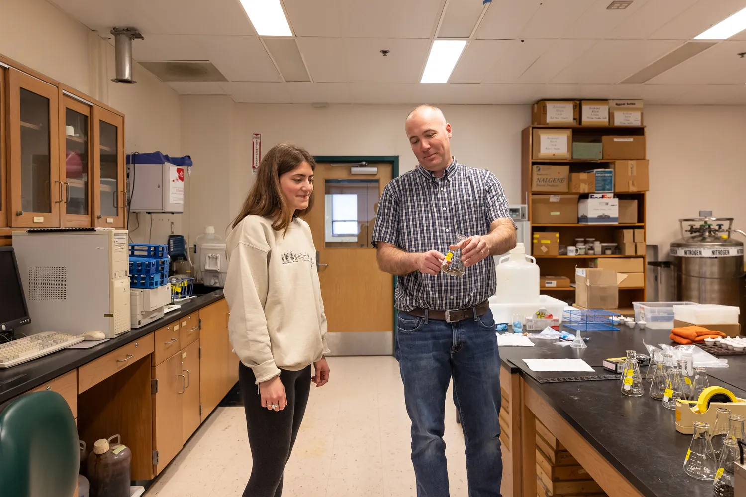 Professor and student in a classroom at the UMCES Appalachian Lab review the contents of a lab beaker.