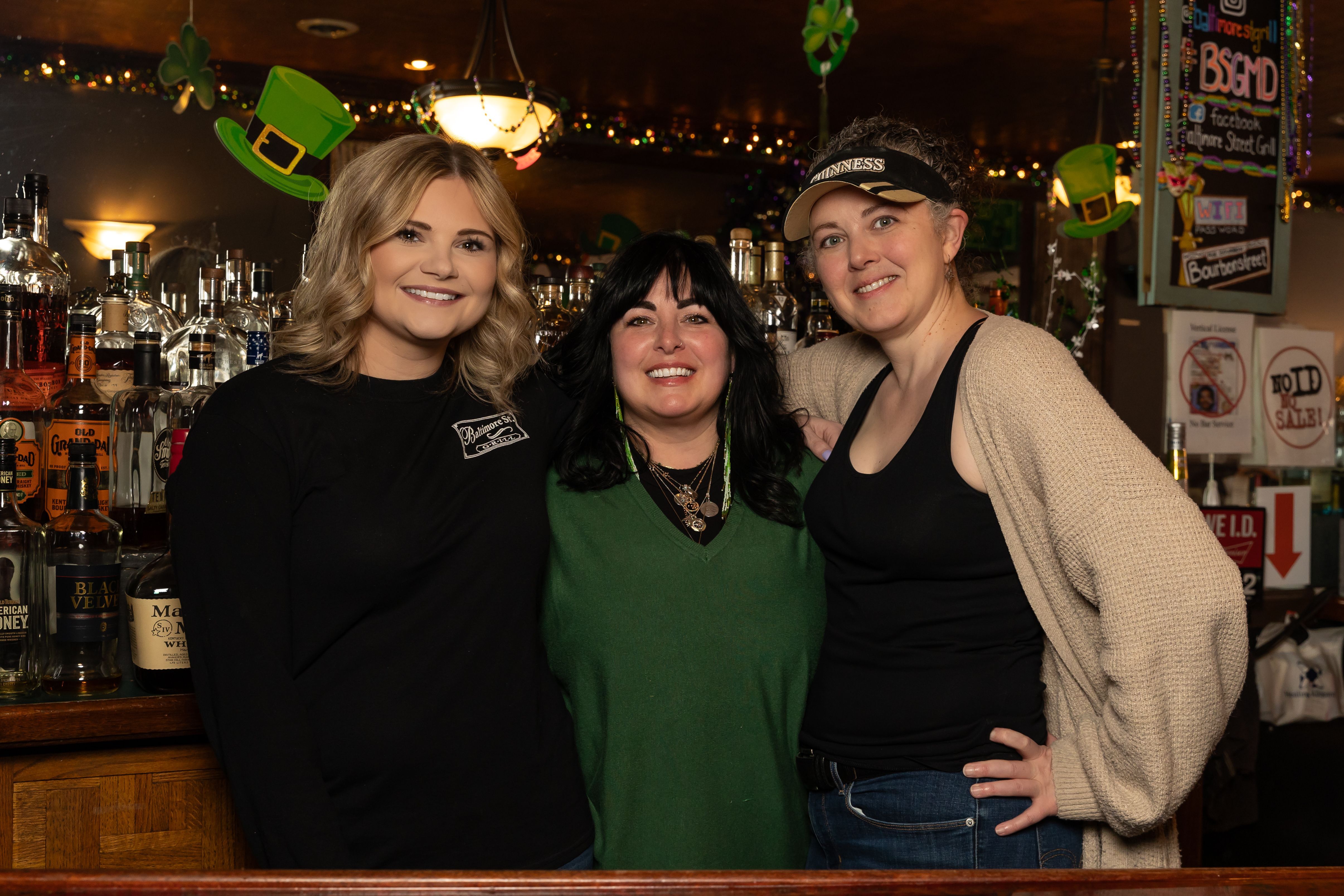 Three employees of the Baltimore Street Grill in Cumberland pose behind the restaurant's bar.